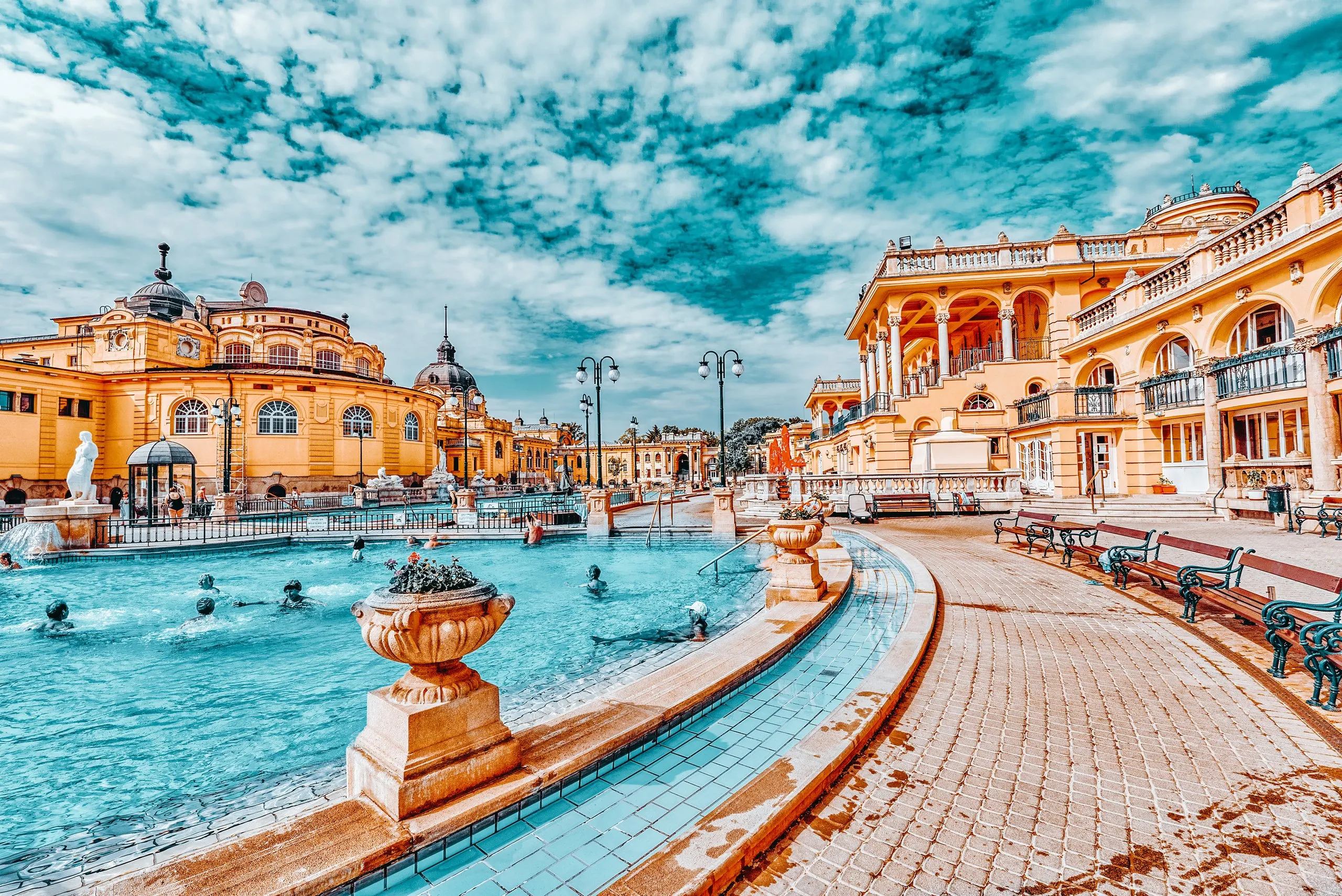 The outdoor pool at Szechenyi Baths, bathers in the steaming water below the yellow neo-baroque facade.