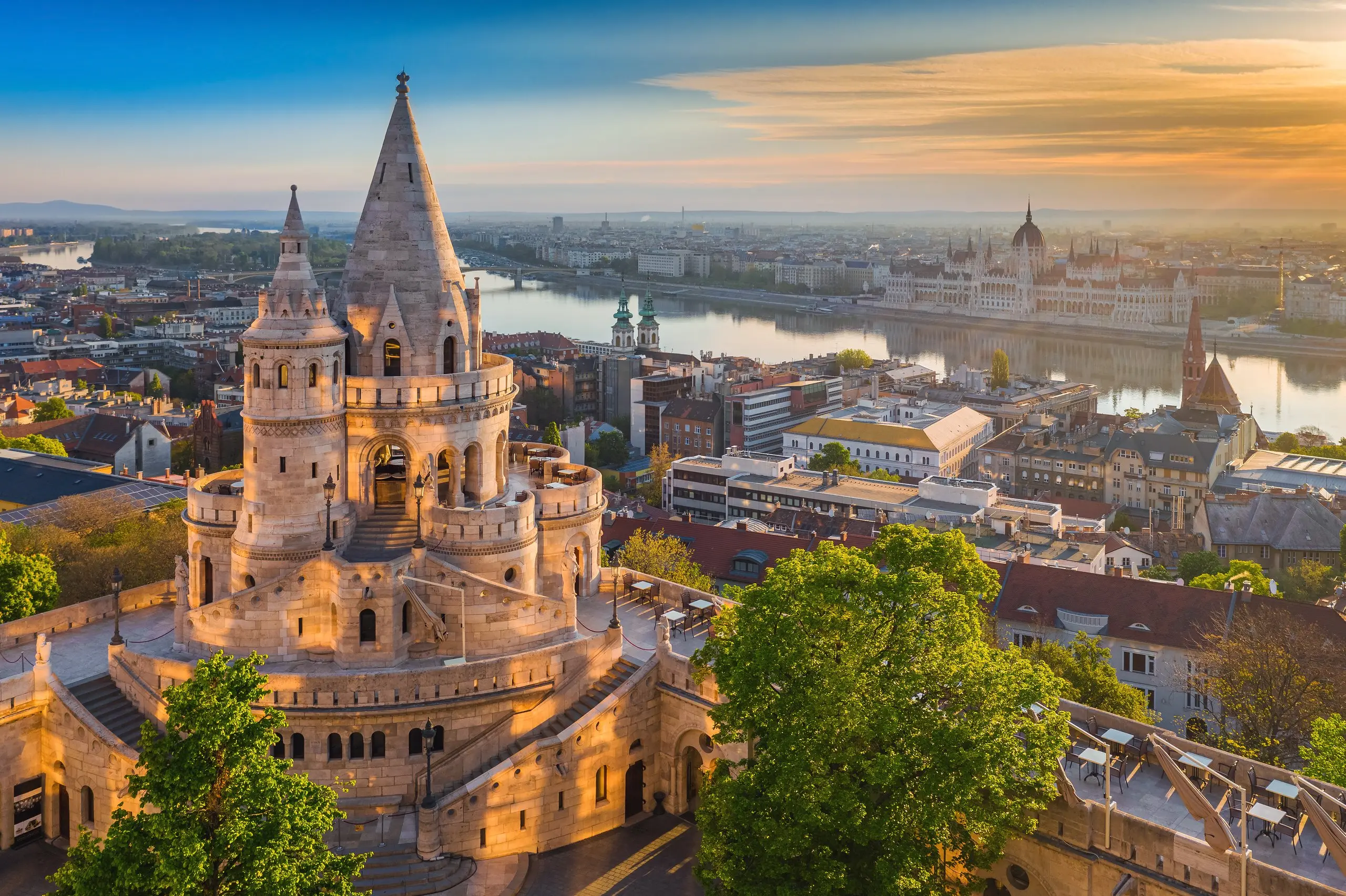 Fisherman's Bastion at sunrise, its white stone turrets above the Danube with the Hungarian Parliament on the far bank.