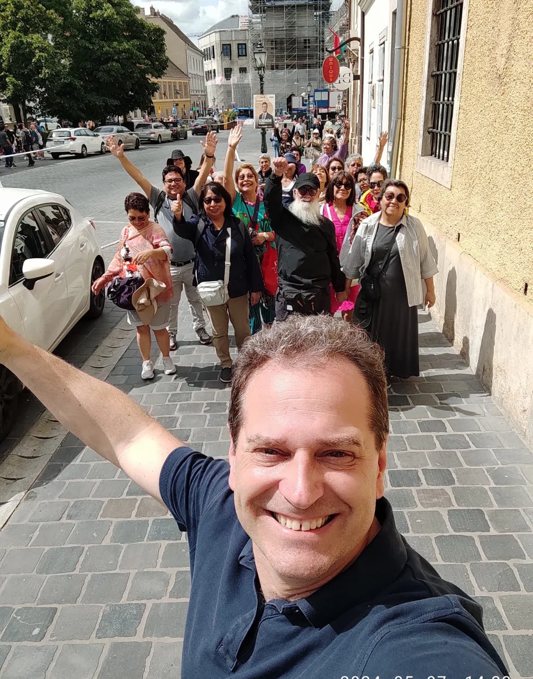 A full group on a Castle District street, all of them waving at the camera